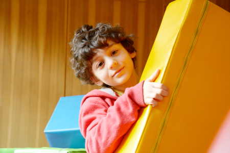 Kind mit lockigen Haaren spielt mit bunten Bauklötzen